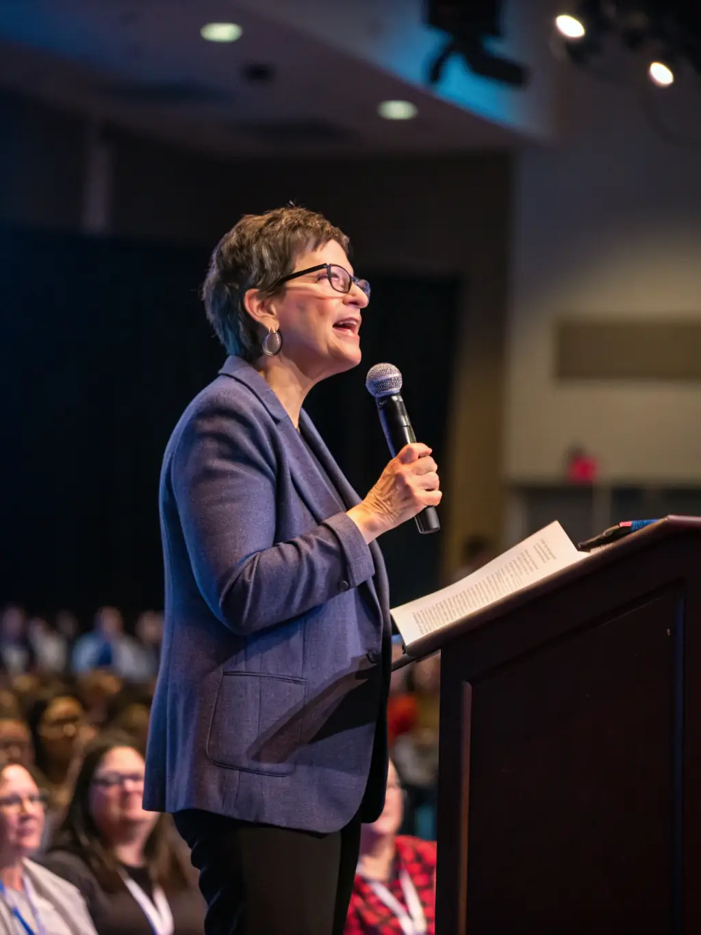 A photograph of a keynote speaker passionately addressing a large audience at a startup conference, emphasizing the importance of innovation and investment.